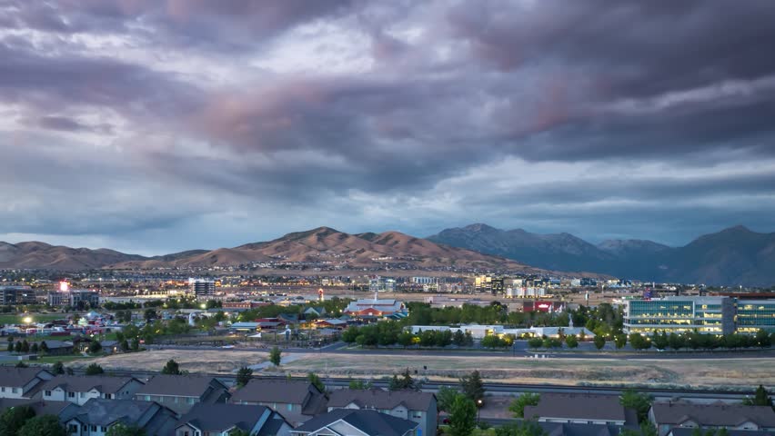 Lehi, Utah and Silicon Slopes from twilight to nighttime with the FrontRunner commuter train passing through - sliding aerial hyper lapse