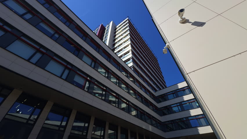 Hospital: Modern Architectures beauty contrasts stunningly with a vibrant blue sky and towering urban skyscrapers