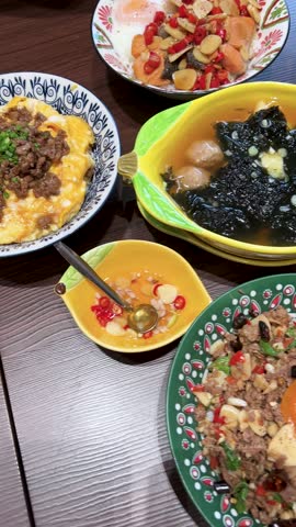 Overhead camera pans across a vibrant Thai meal with rice bowl, marinated beef, seaweed soup, and assorted side dishes under bright indoor lighting