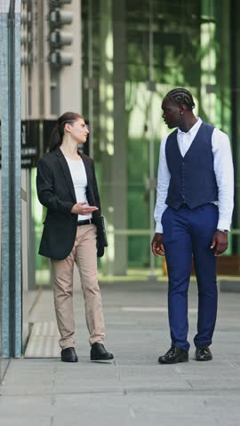 Professional businesspeople walking and discussing strategy outside modern glass office building in Melbourne