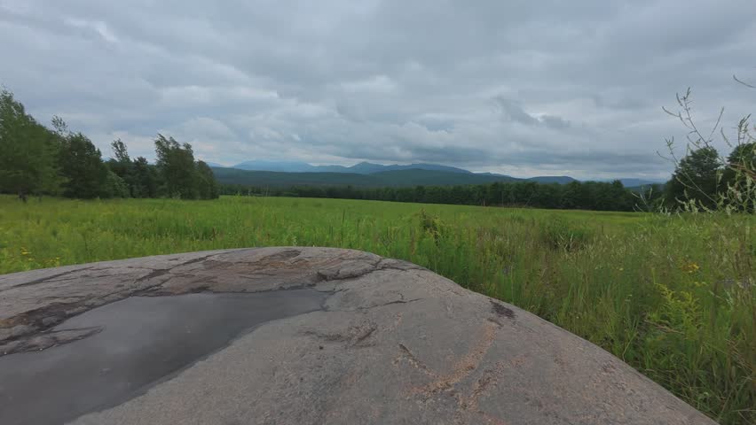 Ground level time
lapse in the Adirondack Mountains of New York near Saranac Lake looking at high peaks with fast moving dark clouds and reflection from a small puddle on a large boulder.