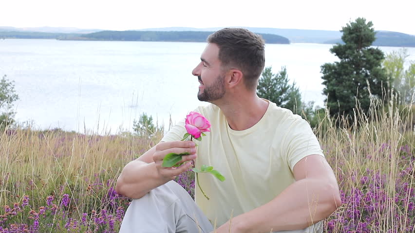 Man smelling a flower in stunning natural setting 