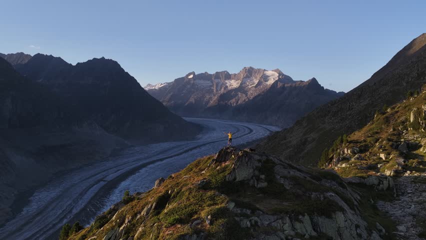 Aerial view of the Aletsch Glacier snaking between the mountains, showcasing the stark contrast of ice and rock, Fieschertal, Valais, Switzerland.