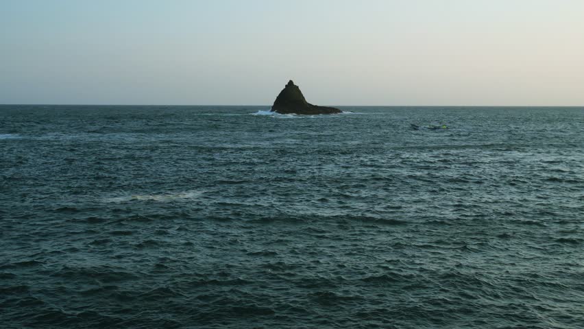 waves crashing on Black Sand beach,
Seascape against clear blue sky with rocky island