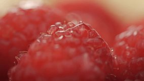 A rotating macro shot of a fresh raspberry covered in glistening water droplets, showcasing its vibrant red drupelets in stunning detail - Powered by Shutterstock - Get 15% off with code: PIKWIZARD15