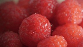 A close-up of a fresh raspberry with water droplets splashing onto its surface in slow motion - Powered by Shutterstock - Get 15% off with code: PIKWIZARD15