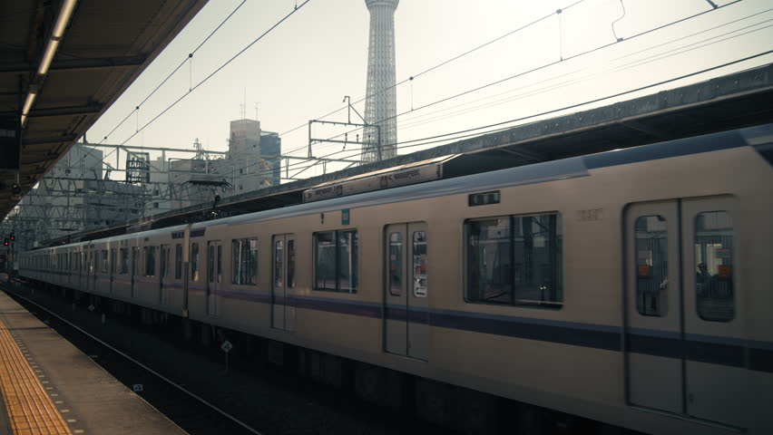 Commuter Train Departing Tokyo Station with Skytree Tower in Background
