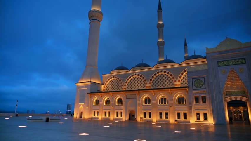 Evening view of the Çamlıca Mosque in Istanbul, Turkey, with its grand white stone facade beautifully illuminated against the sky.