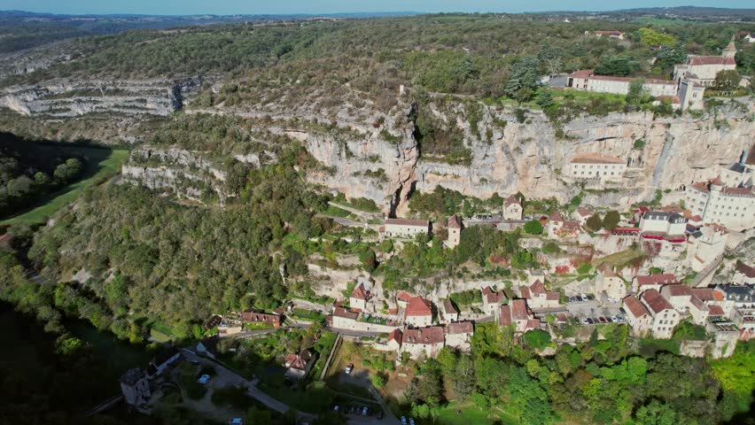 Cliffside Rocamadour village in verdant landscape, aerial view