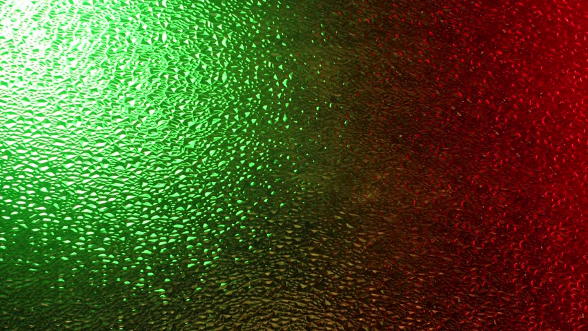 The face of a woman with curls touches textured frosted glass, illuminated by dramatic red and green light. The shapes are softened by the texture of the glass, creating a mysterious, artistic