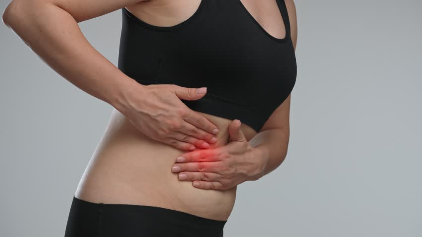 A woman clutching her abdomen, which is highlighted in red, indicating discomfort or pain. Concept of health, treatment and pain relief.
