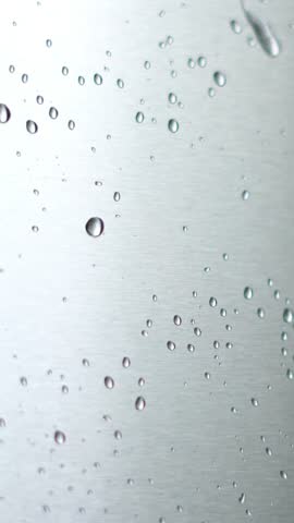 Water drops flowing smoothly on a surface. closeup vertical video footage. short video