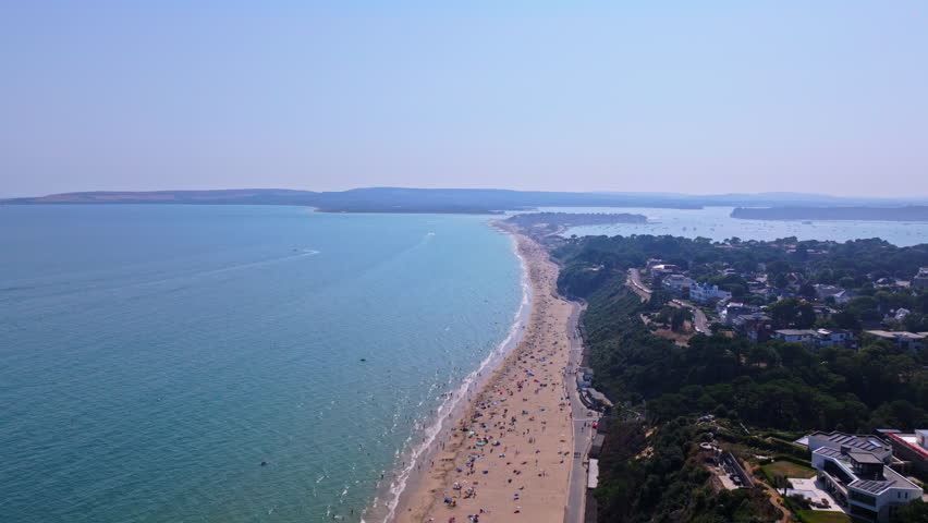 High aerial tracking shot away from beach with Sandbanks and Poole harbour in the distance