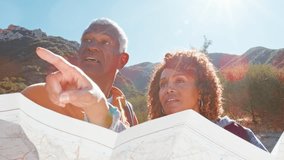 Senior Couple Looking At Map As They Hike Along Trail In Countryside Together - Powered by Shutterstock - Get 15% off with code: PIKWIZARD15