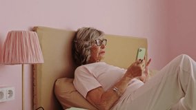 Elderly woman using smartphone in bed, slow motion - Powered by Shutterstock - Get 15% off with code: PIKWIZARD15