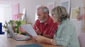 Senior couple examining documents and using laptop in slow motion - Powered by Shutterstock - Get 15% off with code: PIKWIZARD15