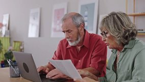 Senior couple discussing documents and using laptop in slow motion - Powered by Shutterstock - Get 15% off with code: PIKWIZARD15