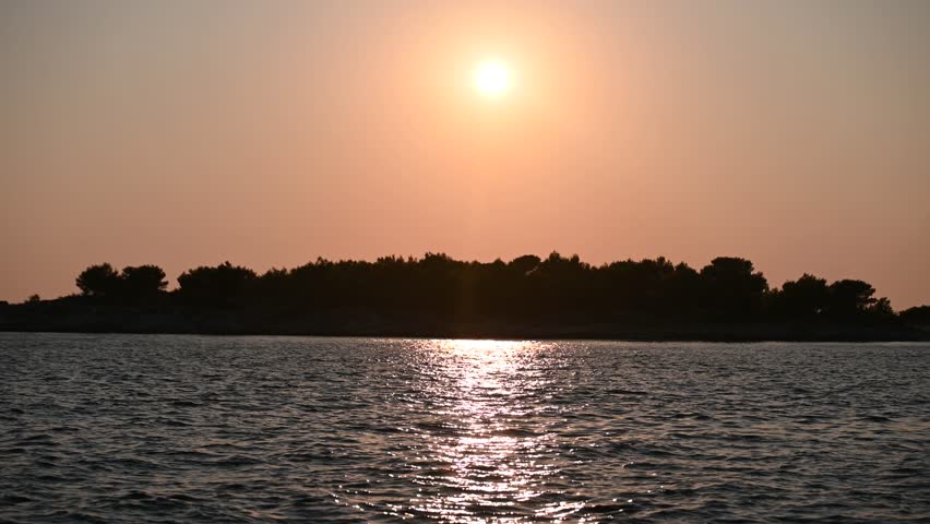 Beautiful sunset over the sea in summer. Orange sky and reflection of the sun on the water.