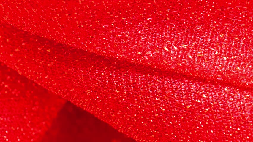 Red glitter wallpaper. Red shiny fabric background.Christmas and New Year background.iridescent gradient texture.Folds of shiny fabric in red tones. 4k footage