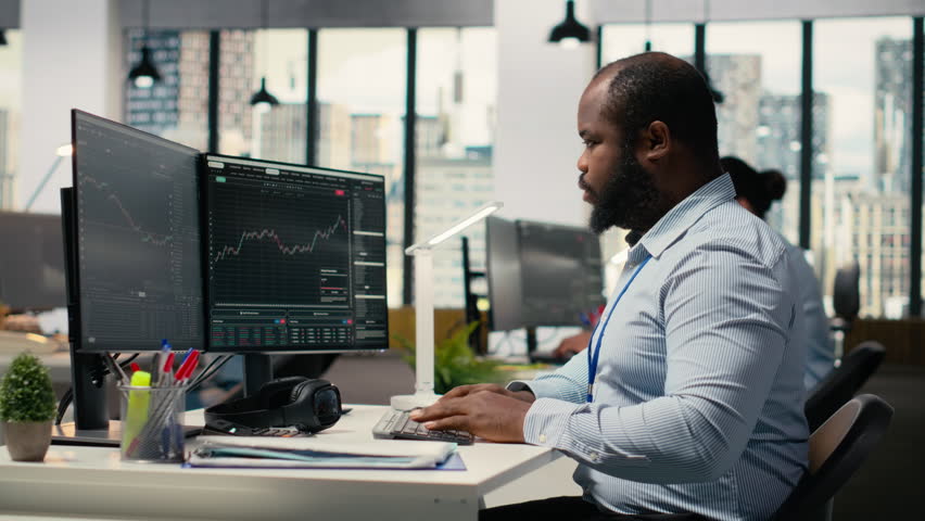 Teamworking traders in office work together to resolve security alert after hacker uses exploit to penetrate systems. Team of prop firm colleagues brainstorm how to protect from cyberattack, camera B