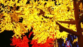 Tree illuminated with warm yellow and red LED lights in nighttime scene, horizontal format. - Powered by Shutterstock - Get 15% off with code: PIKWIZARD15