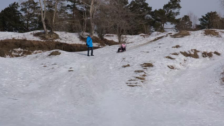 Grandmother with granddaughter having fun on the toboggan hill. Family having fun outdoors in winter on sledge . Family winter time.	