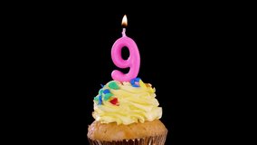 A single cupcake with yellow frosting and a lit pink number nine candle, isolated on a black background, bright studio lighting, no visible movement - Powered by Shutterstock - Get 15% off with code: PIKWIZARD15