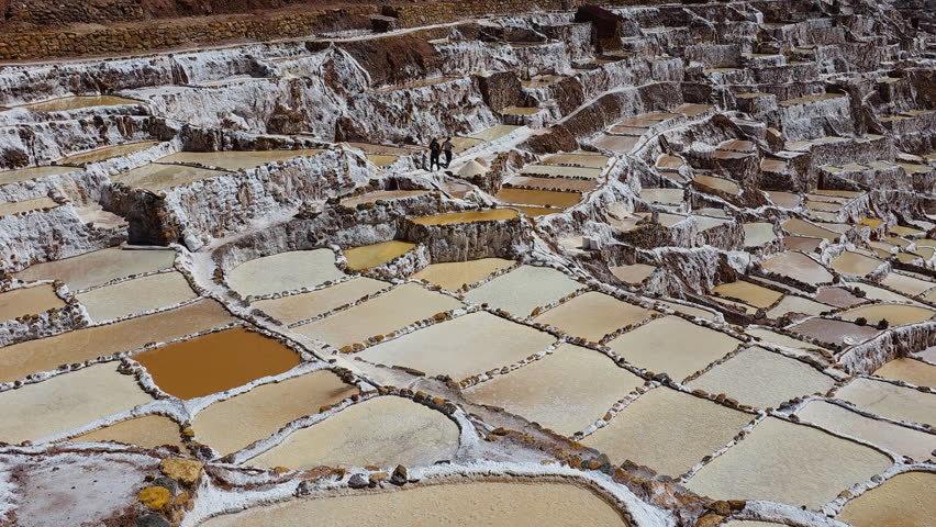 Pan shot captures the impressive terraced salt ponds of the Maras Salt Flats, showcasing this unique and beautiful landscape in the Sacred Valley, Peru.