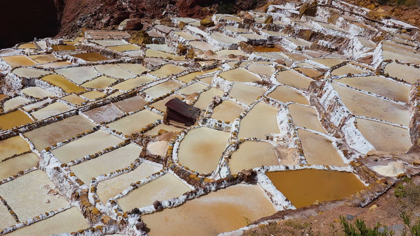 Pan left shot captures the impressive terraced salt ponds of the Maras Salt Flats, showcasing this unique and beautiful landscape in the Sacred Valley, Peru.
