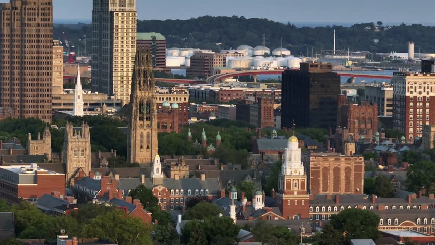 Aerial zoom of historic cathedral and harkness tower in New Haven, Connecticut. Wide shot. Old University and downtown buildings in center. Sunset time.