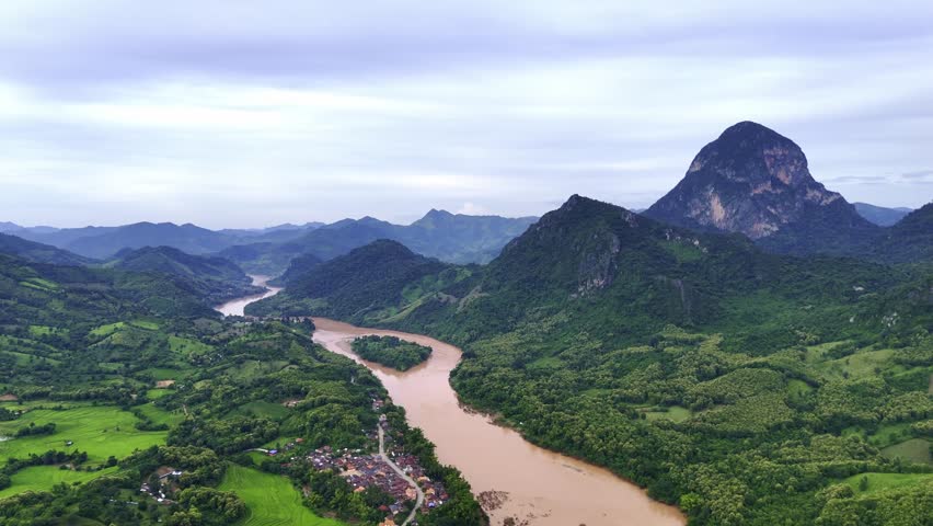 Scenic River and Mountain Landscape: A majestic vista unfolds, revealing a meandering river carving through verdant valleys and framed by imposing mountains under a serene, overcast sky