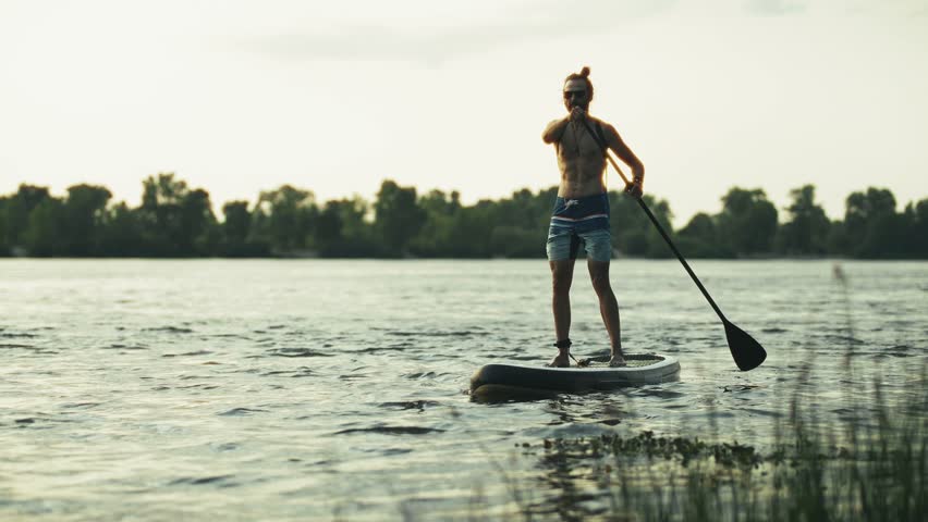SUP Stand Up Paddleboard. Outdoor Summer Recreation. Paddling On  Calm River. Enjoying The Sunset On Water. Healthy Lifestyle And Sport. Paddleboarding Hobby. Peaceful Evening SUP Paddling  Exercise