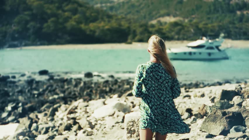 Tourist Standing On Rocky Shoreline. Summer Vacation And Travel. Enjoying Beautiful Coastal Landscape. Boat Trip And Yachting. Luxury Travel And Relaxation. Private Yacht. Summer Holiday Destination