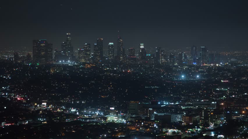 Timelapse drone view of Los Angeles at night, with glowing skyscrapers and bustling streets. A dynamic aerial sweep captures the city’s electric energy, iconic skyline, and cinematic urban pulse.