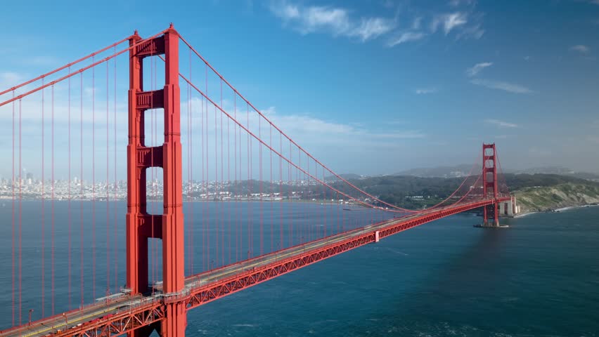 Side drone view of the Golden Gate Bridge with San Francisco’s skyline and Marin Hills in the distance. A timeless blend of engineering, urban energy, and natural beauty across the iconic bay span.