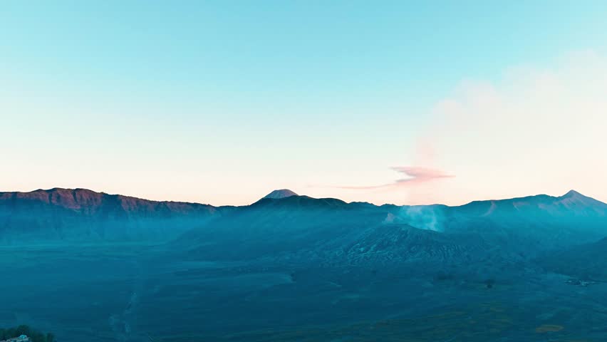 Hyperlapse drone capture of Mount Bromo’s volcanic caldera at sunset in East Java, Indonesia—lit in a fiery glow as clouds and smoke swirl above the ancient volcanic landscape