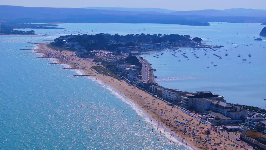 Tracking telephoto aerial shot along the coastline and beach towards the exclusive location of Sandbanks near Poole in Dorset
