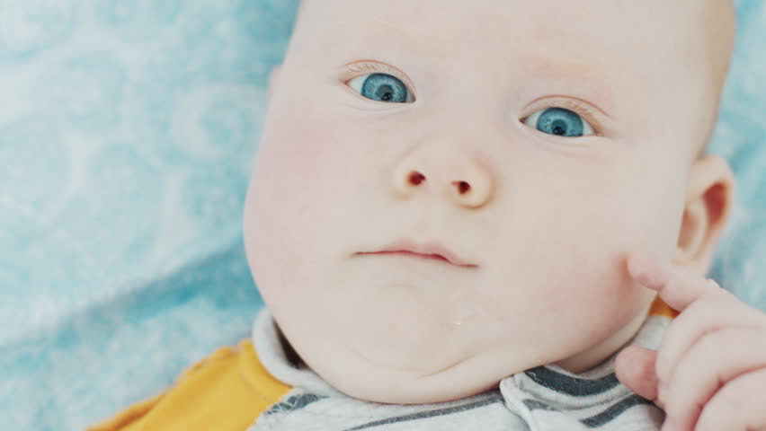 Portrait of the newborn boy (3 months old) with deep blue eyes in the bright white room