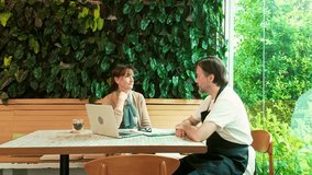 Cafe owner and business advisor working together at a laptop in a cozy cafe setting, reviewing documents and strategies for small business growth and financial planning in a green, modern space. - Powered by Shutterstock - Get 15% off with code: PIKWIZARD15