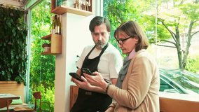 Cafe owner and financial advisor reviewing business data on smart phones inside a cozy coffee shop. Bright natural light and greenery enhance the productive and collaborative workspace atmosphere. - Powered by Shutterstock - Get 15% off with code: PIKWIZARD15