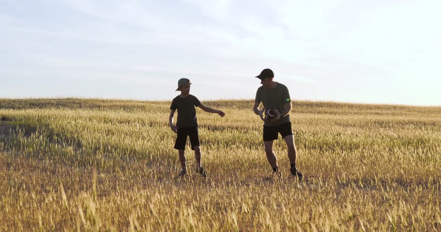 Father and son playing ball together in park sunset. Child and father running through park throwing rugby ball each other. Family playing American football sunset. happy Family activity.