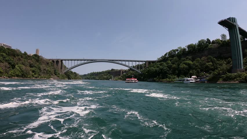 DOLLY SLOW MO - The Niagara Falls (American, Bridal Veil, and Horseshoe Falls), Rainbow Bridge, and the Prospect Point Observation Tower seen from a boat tour on the Niagara River in Ontario, Canada.