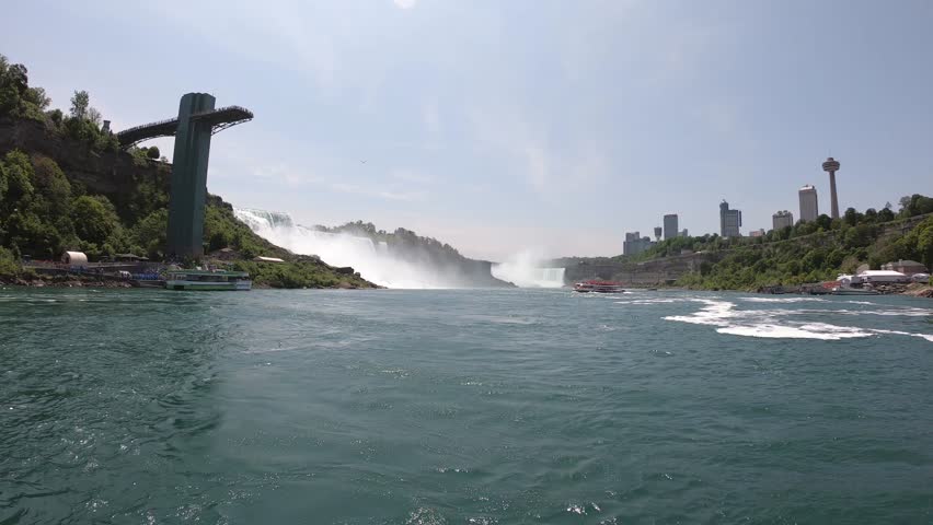 DOLLY SLOW MOTION - The Niagara Falls (American, Bridal Veil, and Horseshoe Falls), and the Prospect Point Observation Tower seen from a boat tour on the Niagara River in Ontario, Canada.