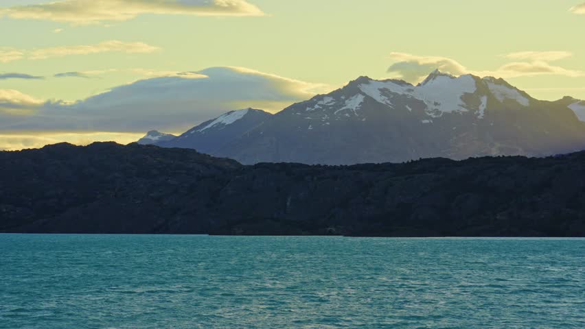Static shot of Lake Belgrano with turquoise waters and the Andes mountains in the background illuminated by warm sunset light, in Perito Moreno National Park, Southern Patagonia, Argentina