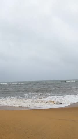 Moody beach landscape under a cloudy sky with soft ocean waves and wet sand reflections. Ideal for themes like solitude, calmness, coastal weather, and natural beauty. Morning on a calm southern beach
