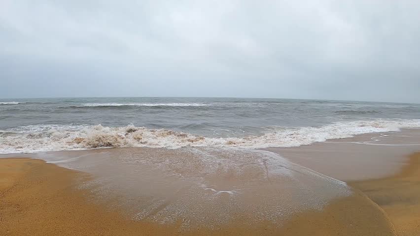 Moody beach landscape under a cloudy sky with soft ocean waves and wet sand reflections. Ideal for themes like solitude, calmness, coastal weather, and natural beauty. Morning on a calm southern beach