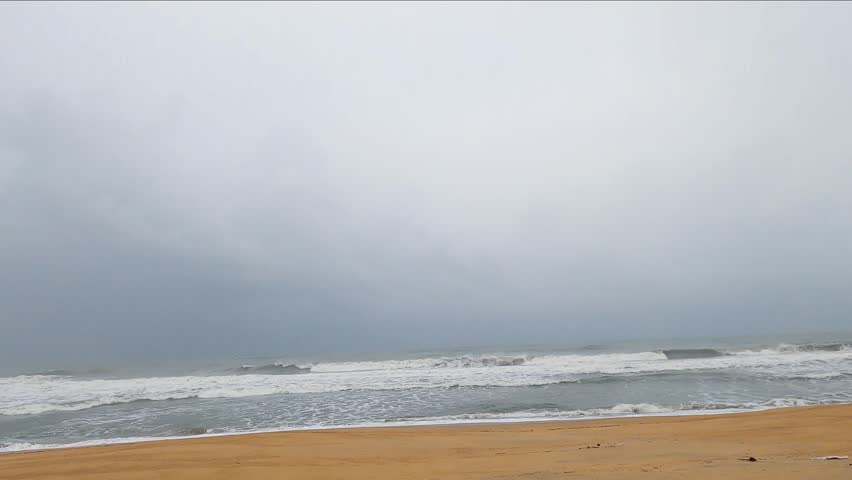 Moody beach landscape under a cloudy sky with soft ocean waves and wet sand reflections. Ideal for themes like solitude, calmness, coastal weather, and natural beauty. Morning on a calm southern beach
