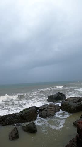 footage of ocean waves gently crashing against tetrapod rock barriers on a serene beach. Ideal for background, nature, travel, or environmental themes with calm sea and sandy shoreline.