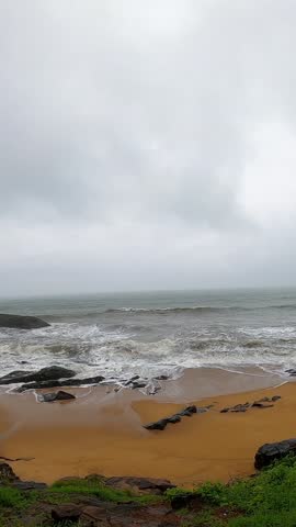 footage of ocean waves gently crashing against tetrapod rock barriers on a serene beach. Ideal for background, nature, travel, or environmental themes with calm sea and sandy shoreline.