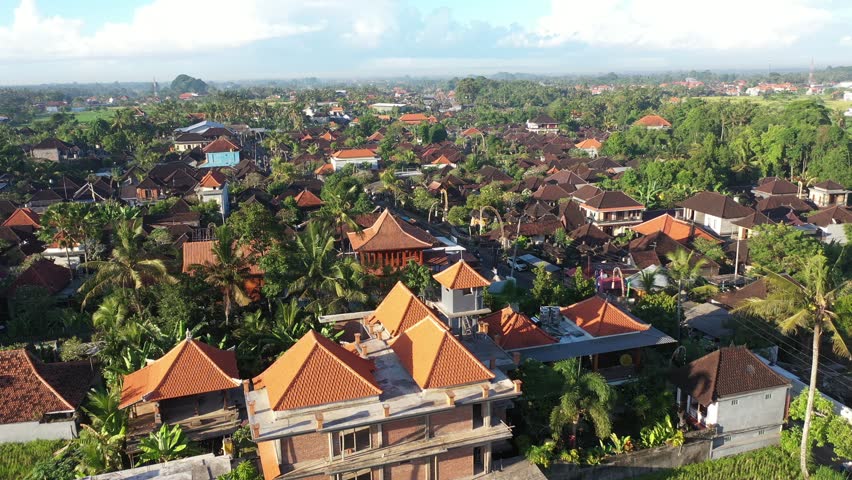 Aerial view of terra cotta roofs interspersed with lush greenery and roads, creating a vibrant tapestry, Ubud, Bali, Indonesia.